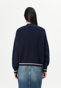 Ναυτικό μπλε πλεκτό πουλόβερ με cropped σχέδιο, ribbed μανσέτες και λευκή ριγέ άκρη. Σημαντική υφή και κουτί σχήμα.