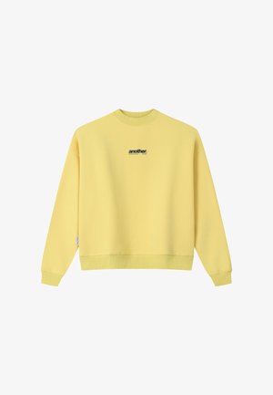 Kollane pika varrukaga ümar kaelusega dressipluus, mille rinnal on keskel väike must "another" tekstilogoga.