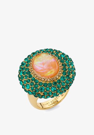 Gouden ring met grote centrale iriserende perzikkleurige steen, omgeven door kleine groene en gouden edelstenen in een cirkelvormig patroon.