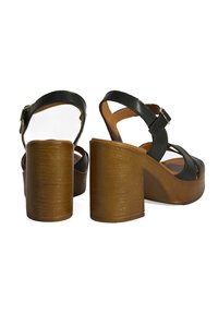 Schwarze Ledersandalen mit Absatz und Holzplattform, ausgestattet mit verstellbaren Knöchelriemen und einem breiten Blockabsatz für Stabilität.
