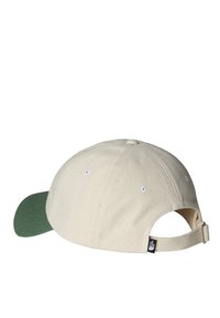 Gorra de algodón blanca con visera verde, que presenta un acabado texturizado, ojales y una correa ajustable en la parte trasera.