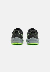 Zapatillas deportivas negras con suelas grises y tracción de un verde brillante, que cuentan con una parte superior de malla, costuras en contraste y un diseño de talón que ofrece soporte.