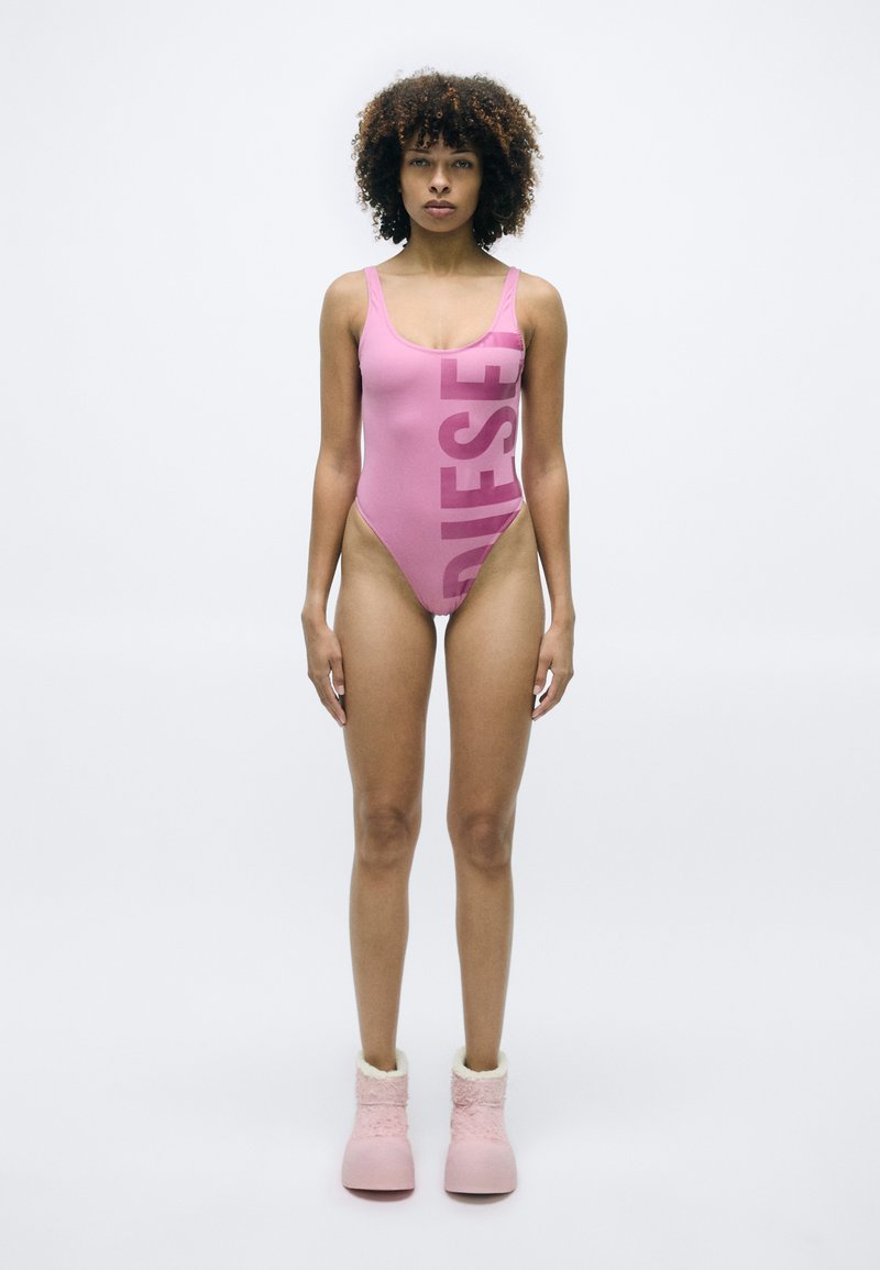 Roze badpak met een gedurfde "DIESEL" print op de voorkant, met een ronde hals en hoge uitsnijdingen aan de benen. Gepaard met roze pluche laarzen.