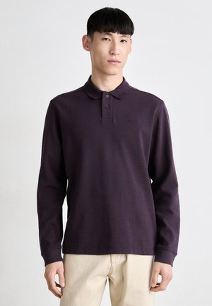 Long-sleeve polo shirt in deep purple with a ribbed texture, three-button placket, and embroidered logo on the left chest.