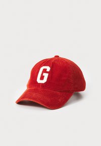 Casquette de baseball en velours côtelé rouge avec un logo "G" blanc, visière incurvée et surface texturée. Détails de couture centrés sur la couronne.