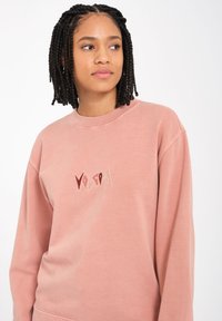 Staubrosa Sweatshirt mit Rundhalsausschnitt, gerippten Bündchen und gesticktem „VOICED“-Logo in verschiedenen Farben auf der Vorderseite. Weiche Stofftextur.