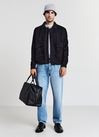 Giubbotto bomber in suede nero, t-shirt grigia chiara, jeans in denim blu, borsa in pelle nera, berretto grigio, scarpe nere. Composizione di un outfit casual.
