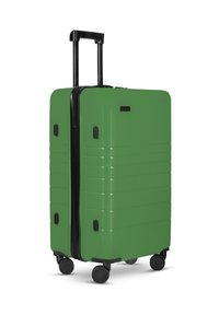Grüner Hartschalenkoffer mit glatter Oberfläche, schwarzem Griff und Rädern. Verfügt über horizontale Rillen an den Seiten und einen Reißverschluss.