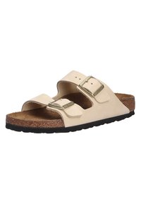 Beige cork footbed sandals with two adjustable straps and metal buckles, featuring a textured insole and a black rubber outsole.