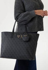 Geantă tote din piele ecologică neagră cu un model embosat, având o insignă aurie cu logo și un mic pouch atașat cu fermoar. Textură moale, design spațios.