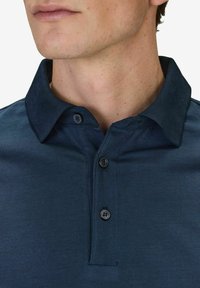 Marinblå polo shirt i mjukt material, med krage, tre knappar och avslappnad passform. Diskret sömnadsdetalj vid fållen.