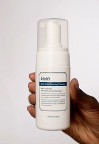 Bouteille en plastique blanche avec un distributeur de pompe transparent. L'étiquette avant présente un texte bleu et une description du produit et de son utilité. Taille de 100 ml.