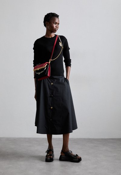 Sort ribbet striktrøje, højtaljet sort nederdel med guldknapper og sorte platform sandaler med guldaccent. Rød og sort crossbody taske.
