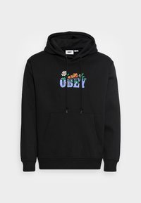 Svart hoodie med framficka, dragsko på huva och broderad grafik med färgglada blommor och texten "OBEY". Mjuk tygkänsla.