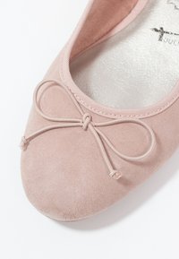Ballet en daim rose avec un bout rond, ornée d'un nœud décoratif en cordon assorti et d'une doublure intérieure lisse et de couleur claire.