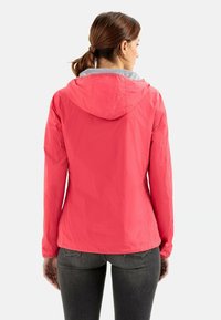 Veste légère et imperméable de couleur rose vif, dotée d'une capuche et d'une doublure grise. Présente un design simple avec des poignets élastiques et une coupe légèrement ajustée.