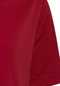 Camicetta rossa a maniche corte, realizzata in tessuto liscio. Presenta un colletto rotondo e una sottile texture, con cuciture pulite lungo i bordi.