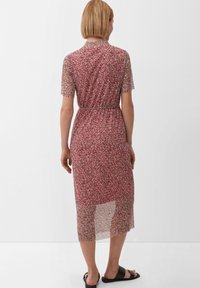 Červené květinové midi šaty s krátkými rukávy, průhlednou tkaninou, pasem s opaskem a mírně průsvitným lemem. V kombinaci s černými skluznými sandály.