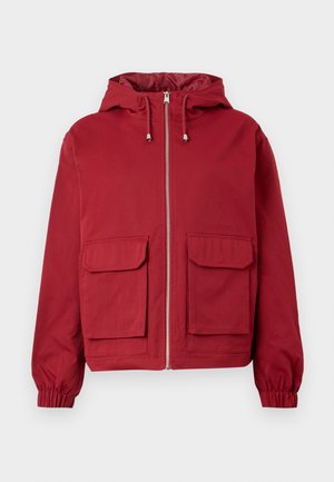 Punainen hupullinen takki, jossa edessä vetoketju, kaksi isoa etutaskua läpällä, joustavat hihansuut ja nyörit hupussa.