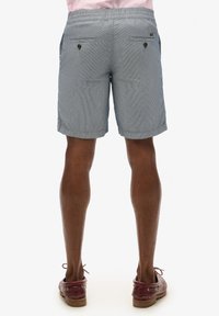 Shorts rayés pour hommes en bleu et blanc, dotés de poches, d'une ceinture douce et d'une coupe décontractée. Tissu texturé avec un motif subtil.
