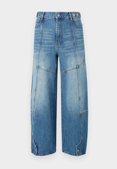 Jeans in denim blu a vita alta e gamba larga con pannelli sbiaditi, cuciture decorative, patte con bottone alle caviglie e chiusura frontale con bottone.