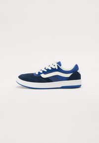 Blue suede sneakers with white and darker blue accents, featuring a round toe, flat sole, and lace-up design. Clear brand logo on heel.