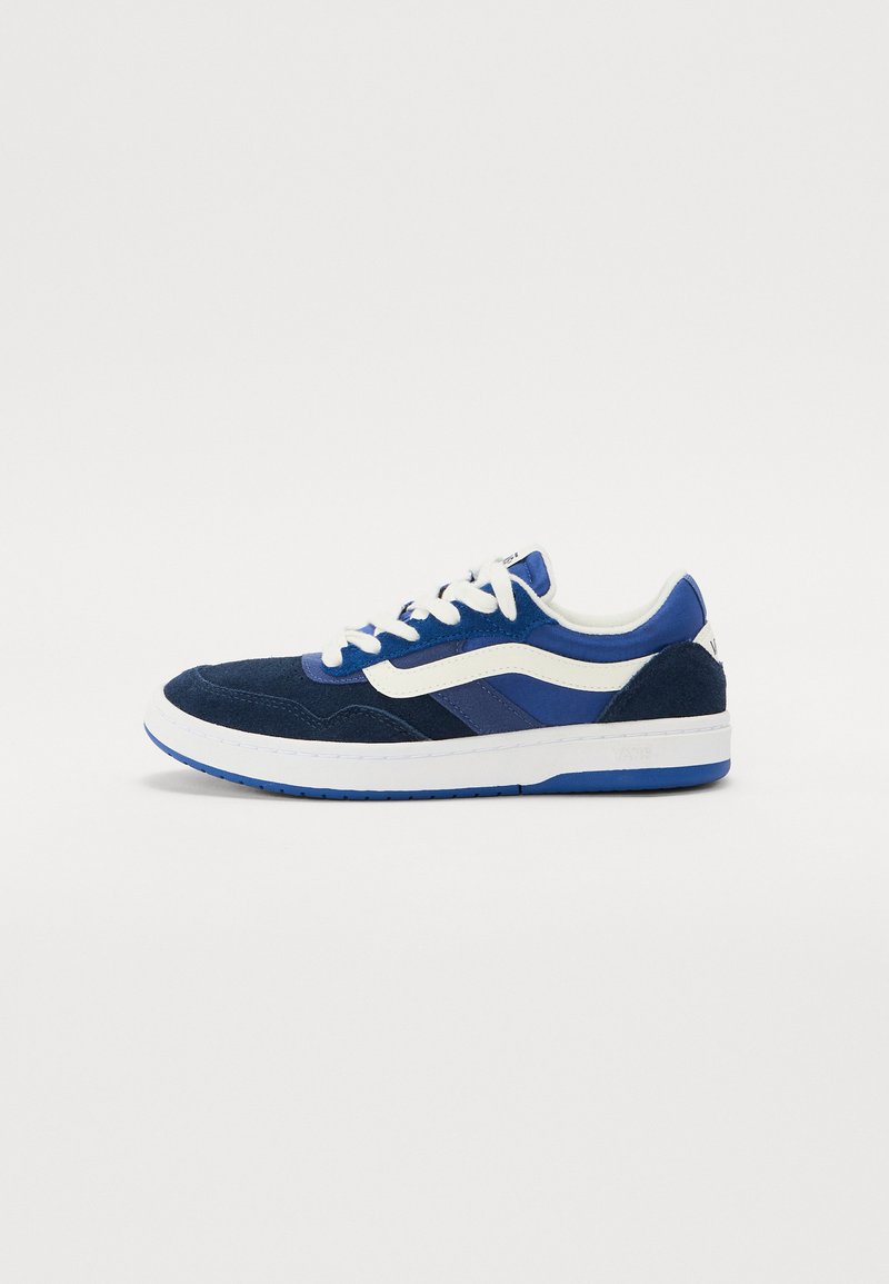 Blue suede sneakers with white and darker blue accents, featuring a round toe, flat sole, and lace-up design. Clear brand logo on heel.