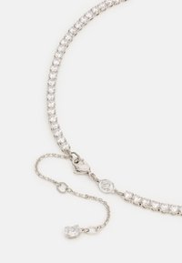 Náhrdelník s kamienkami z strieborného kovu. Obsahuje radu priehľadných kamienkov, prepojených retiazkou s zapínaním. Súčasťou je aj nastaviteľná predlžovacia retiazka.