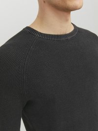 Maglione a coste nero con scollo rotondo e superficie strutturata. Dettagli delle cuciture visibili lungo le spalle e i lati.