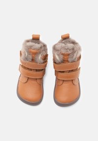 Bottes en cuir marron avec doublure en fausse fourrure, dotées de deux lanières réglables, bout arrondi et semelle en caoutchouc. Texture douce et conception durable.