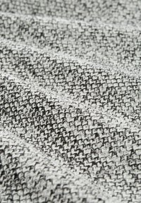 Textiel bestaande uit zwart en witte geweven vezels, met een gestructureerd oppervlak met een subtiele ruitpatroon en variërende draaddiktes.