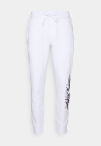 White sweatpants made of cotton blend, featuring a drawstring waist, tapered legs, and side logo in black and red text along the left leg.