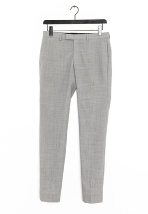 Pantalon sur mesure gris clair avec passants de ceinture et poches avant suspendu à un cintre noir sur fond blanc.