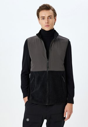 Herrenweste mit einem dunkelgrauen Oberteil und schwarzem Fleece-Untereinsatz, mit Reißverschluss und seitlichen Taschen für praktische Nutzung. Weicher Stoff über die gesamte Weste.