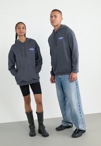 Gray hoodies with front pockets and drawstrings, black bike shorts, knee-high black boots with silver accents, and loose blue jeans.