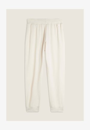 Joggers color crema realizzati in tessuto morbido, dotati di una cintura elastica e orli arricciati. Include un piccolo tag con logo sulla cintura.