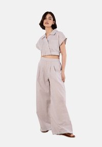 Ensemble à rayures composé d'une chemise courte à col avec des manches courtes et d'un pantalon large. Le matériau semble léger et texturé.