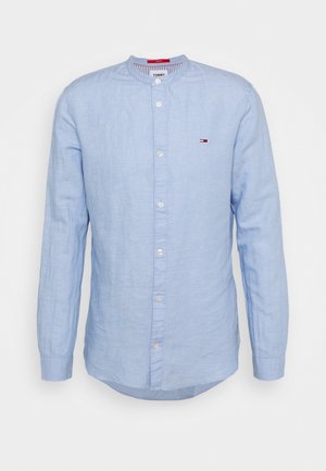 Camisa de lino de manga larga de color azul claro con cuello mao, botones blancos en la parte delantera y pequeño logo de Tommy Hilfiger en el pecho izquierdo.
