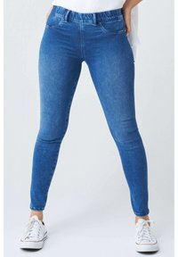 Modré džíny skinny mají elastický pas, pět kapsových provedení a délku do kotníků. Materiál má mírně opotřebovaný vzhled.