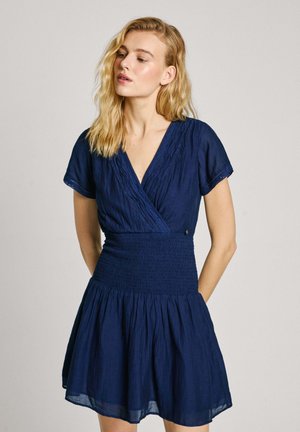 Navy blue dress made of lightweight fabric, featuring a wrap design, short sleeves, a smocked waist, and a flared skirt.
