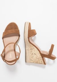 Bruine suède wedge sandalen met een kurk- en juteplatform, voorzien van twee brede banden en een enkelgesp voor een veilige pasvorm.