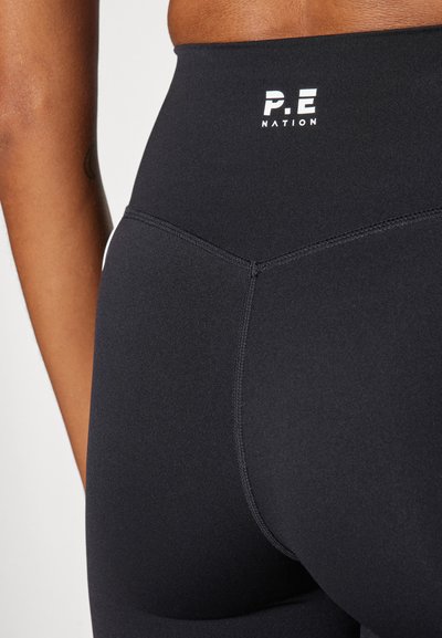 Black high-waisted leggings made from a smooth, stretchy material. Features P.E Nation logo on the waistband and flat seams for comfort.