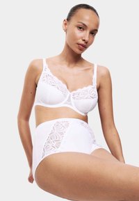 Vitt set med bh och högmidjad trosa med intrikata spetsdetaljer och prickigt mönster, justerbara band och slät textur.