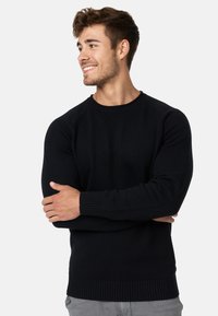 Svart strikkegenser med rund hals, ribbestrikkede mansjetter og nederkant. Designet har lange ermer og en glatt tekstur.