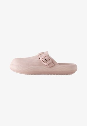 Zoccolo rosa chiaro slip-on con superficie texture e cinturino regolabile con fibbia sulla parte superiore, suola piatta e design con punta chiusa.