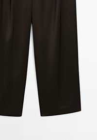 Pantalon noir à jambes larges avec une texture lisse et brillante. Il présente une taille haute et une coupe droite et épurée à l'ourlet. Design simple et minimaliste.