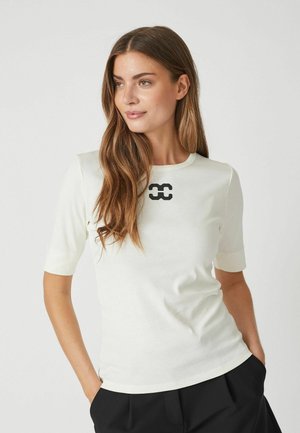 Cream-colored fitted t-shirt with short sleeves and a round neckline. Features a black abstract logo at the center. Soft, smooth fabric.