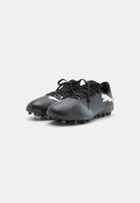 Botas de fútbol negras con parte superior sintética texturizada, cordones negros y un acento de logotipo blanco. Cuenta con tacos moldeados para tracción en césped.