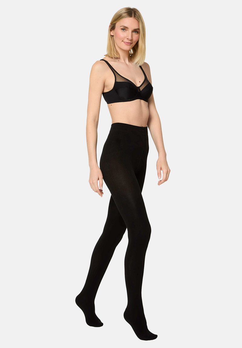 Tights negros opacos con una textura suave, diseño de cintura alta y una silueta ajustada, exhibidos en un modelo con un sujetador negro a juego.