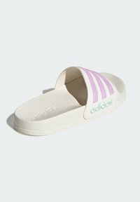 White slide sandal with a textured surface; features three pink stripes and "adidas" logo in mint green on the strap. Flat profile.